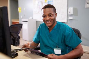 Portrait Of Male Nurse Working At Nurses Station