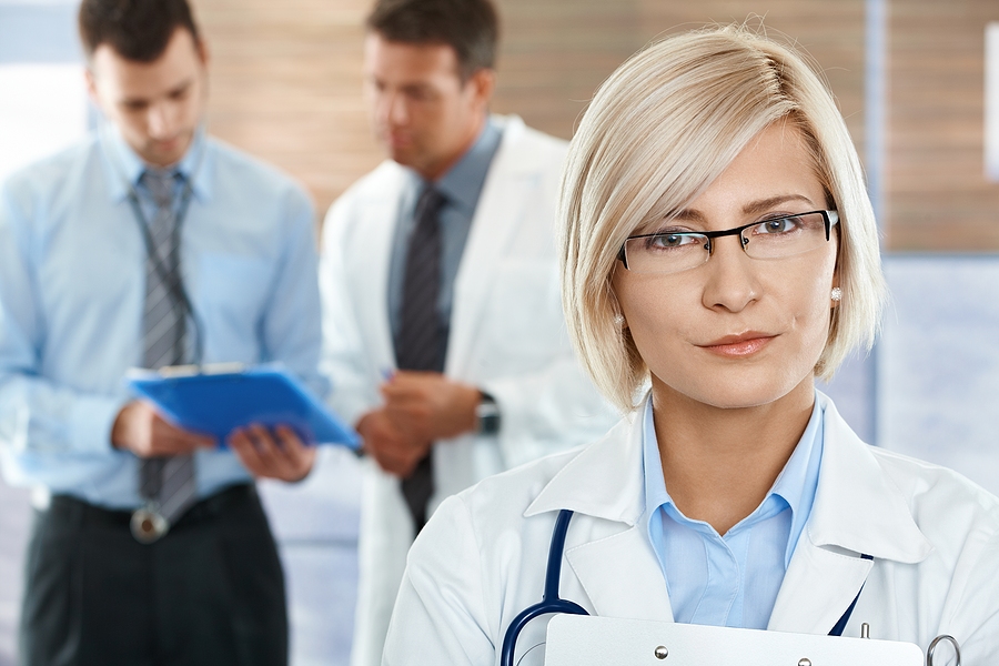 Medical assistant wearing glasses and a white medical coat.