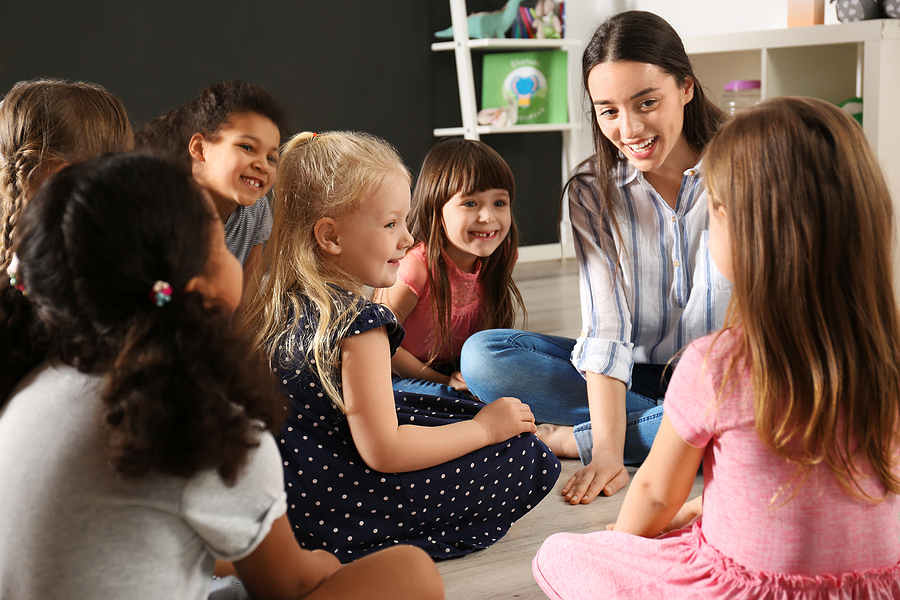 Young teacher with a group of young children in a classroom.