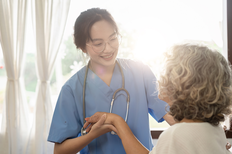 Young female medical assistant smiling and speaking to an older woman patient to comfort her