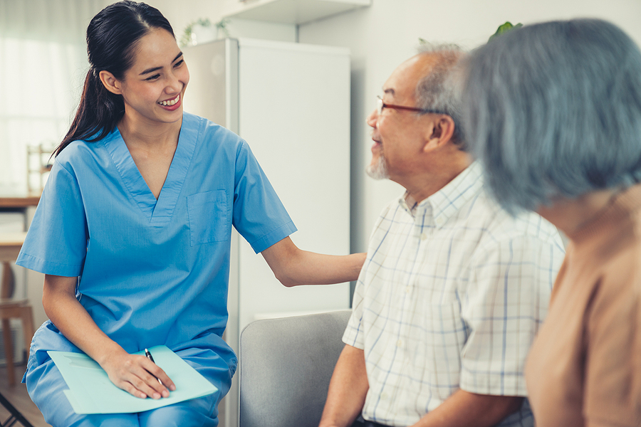 Medical assistant talking to an elderly male patient.