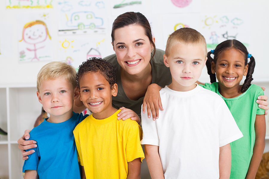 Preschool teacher standing with a small group of young students.