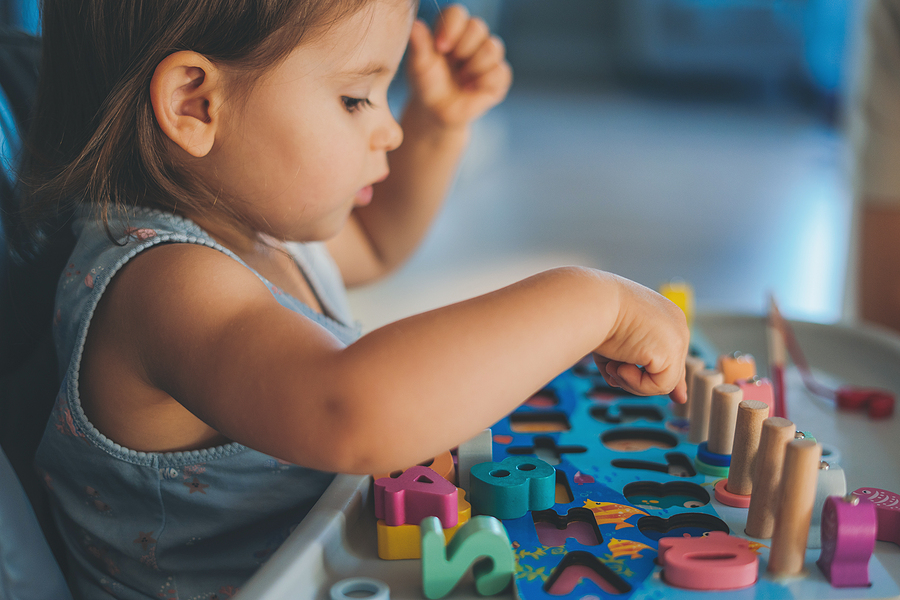 Young preschool student playing with an alphabet puzzle.