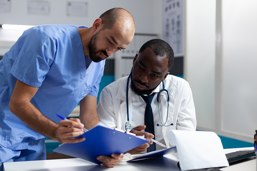 Medical assistant looking over a patient chart with a doctor.
