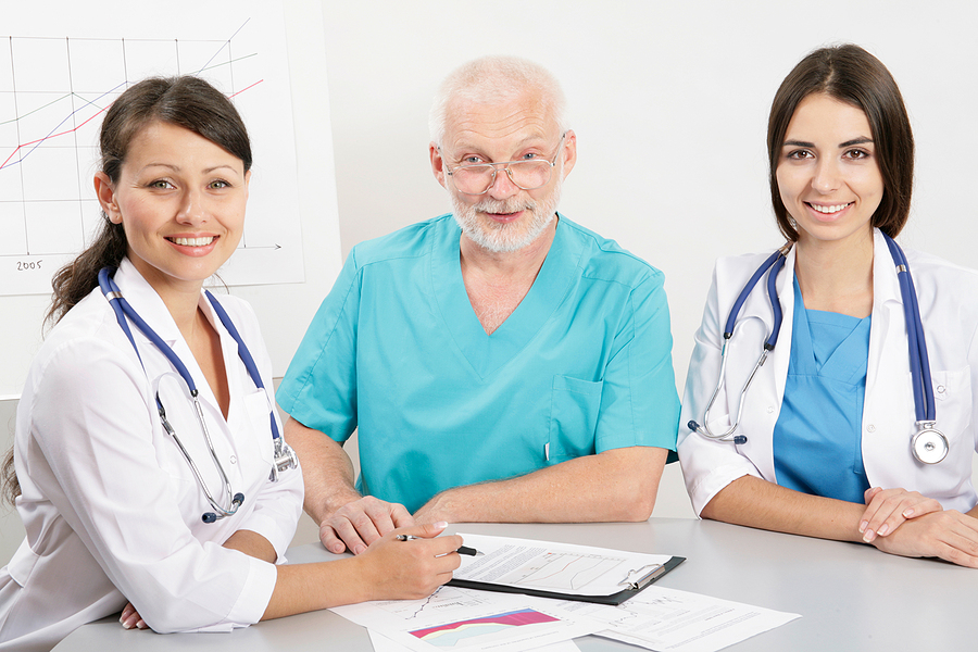 Nurses and a medical assistant looking over patient charts.