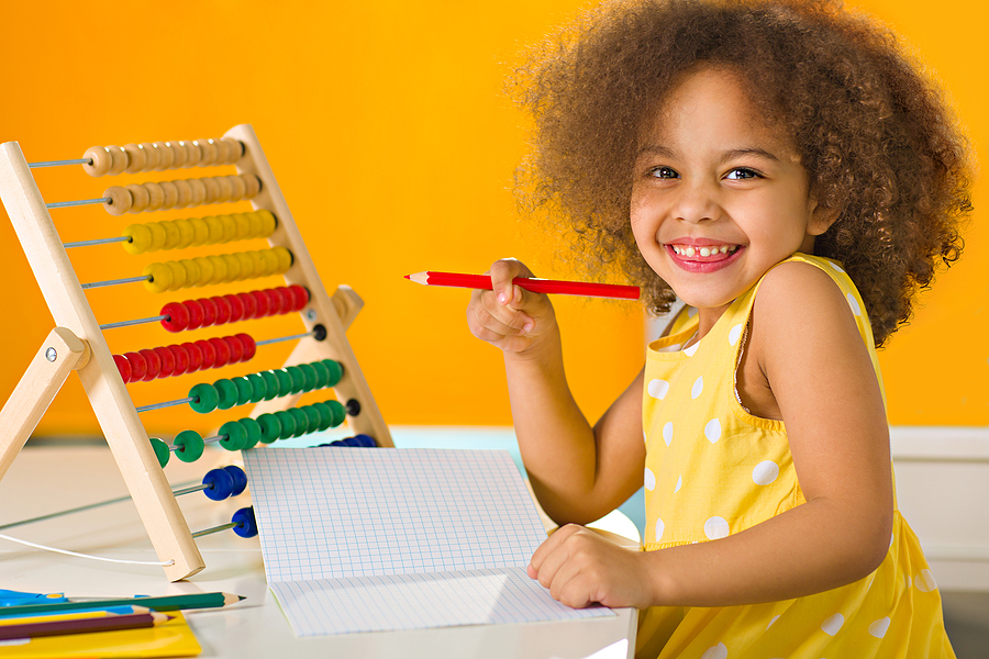 Young student smiling and holding a pencil.