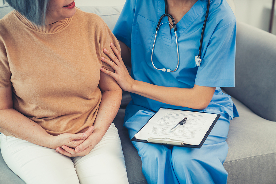 Medical assistant sitting next to a female patient.