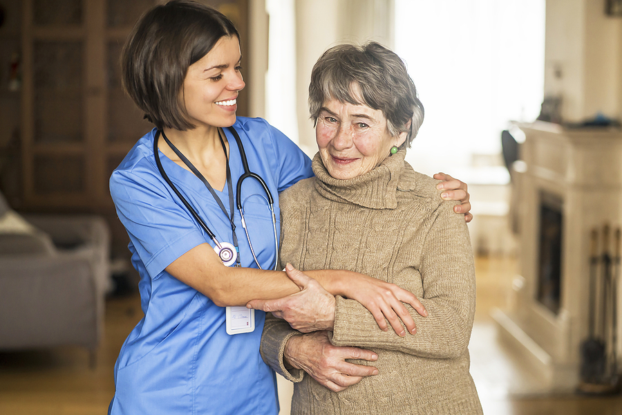 Medical assistant helping an elderly woman walk.