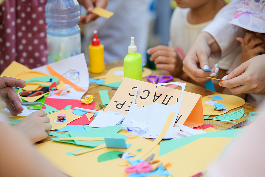 Young students working on an art project with construction paper and glue.