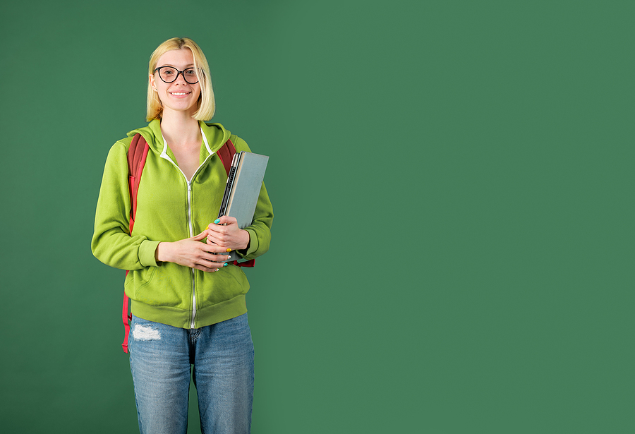 Smiling college student wearing a backpack and holding books.