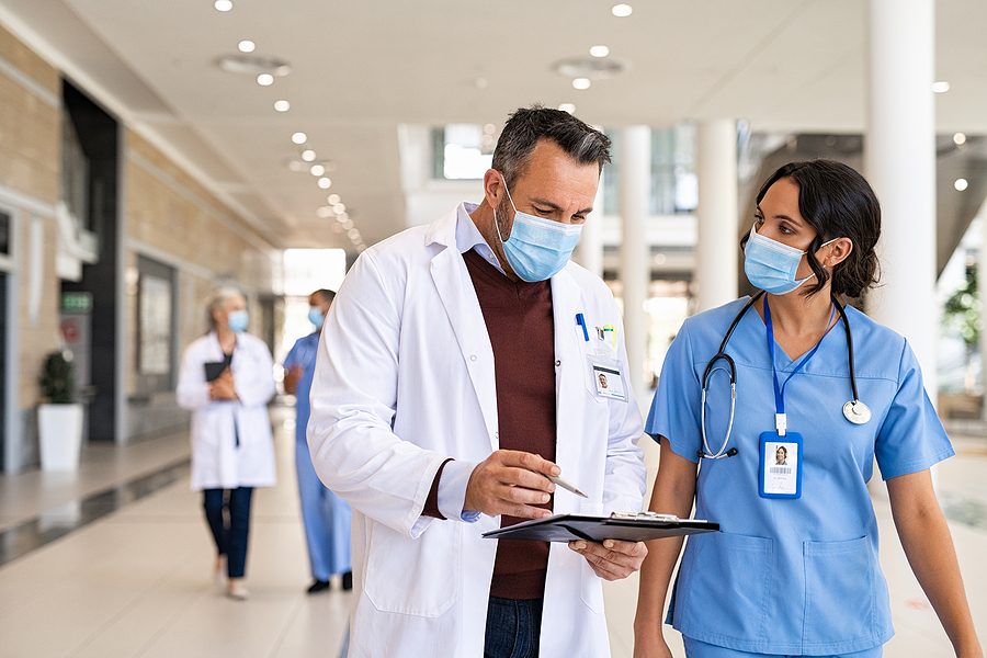 Medical assistant walking through a healthcare facility with a doctor.