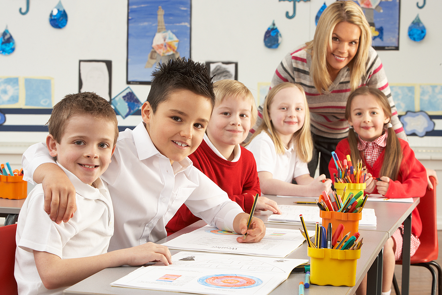 Smiling teacher with students in a classroom.