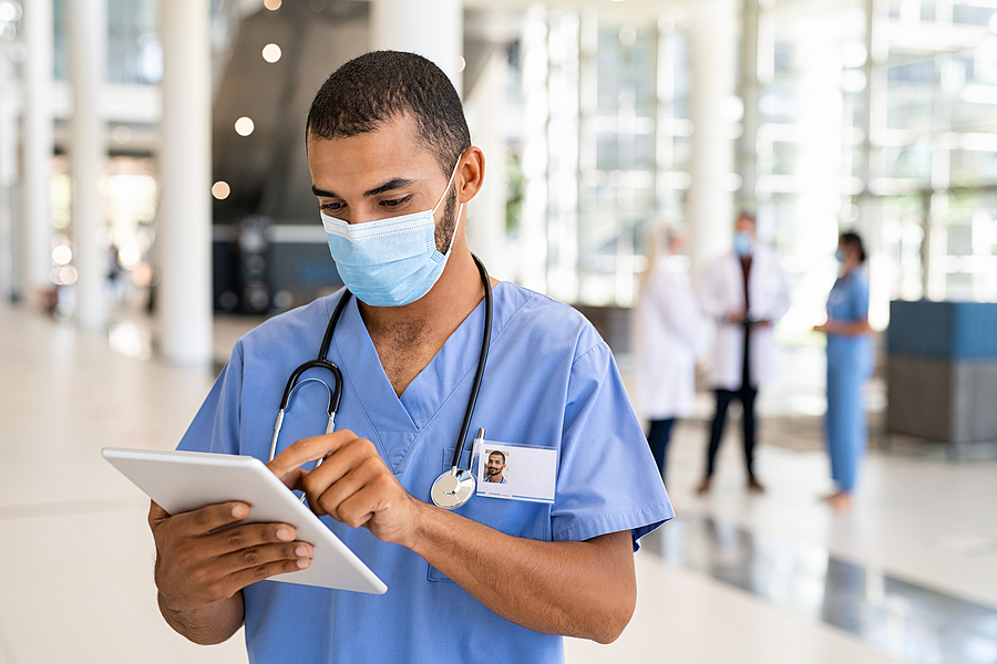 Medical assistant looking at a digital device standing in a hospital.