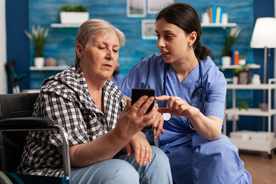 Medical assistant talking with a patient sitting in a wheelchair.