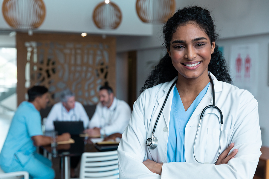 Smiling medical assistant wearing a lab coat and stethoscope.
