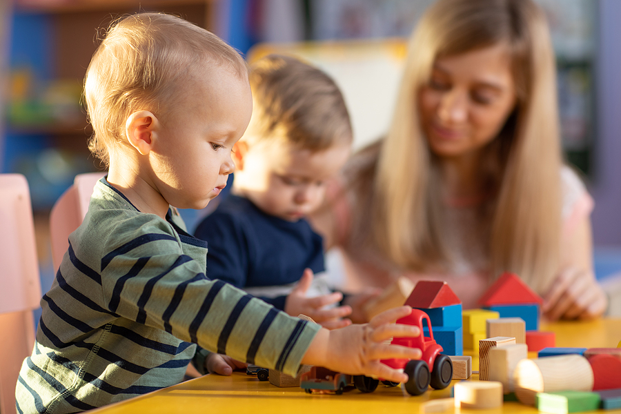 New preschool tracher with young students playing with toys.