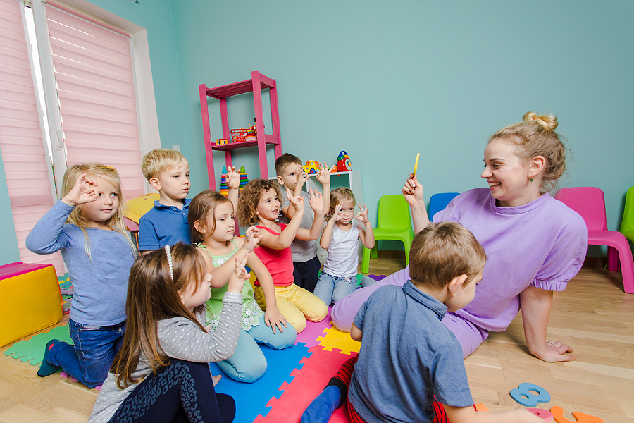 Preschool teaching interacting with young students.