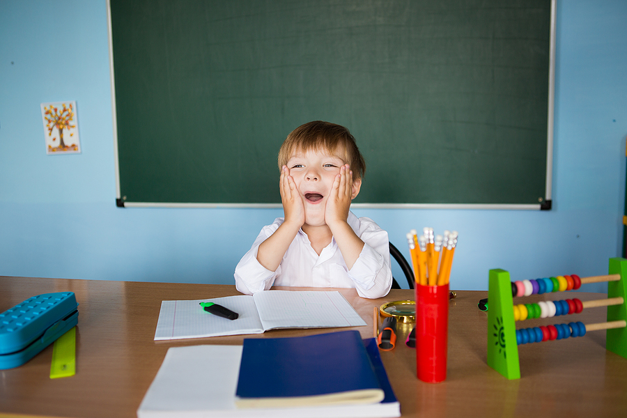 Small student sitting at the teacher's desk.