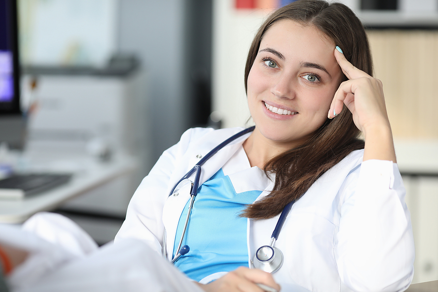 Mediacl assistant smiling while sitting at a desk.