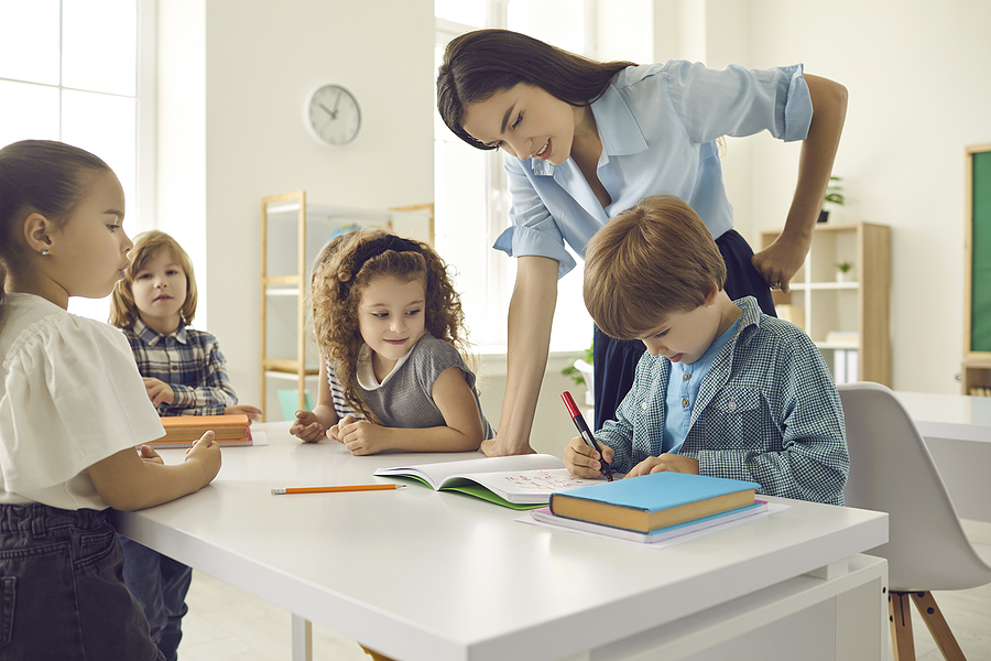Teacher helping a young student with their class work.