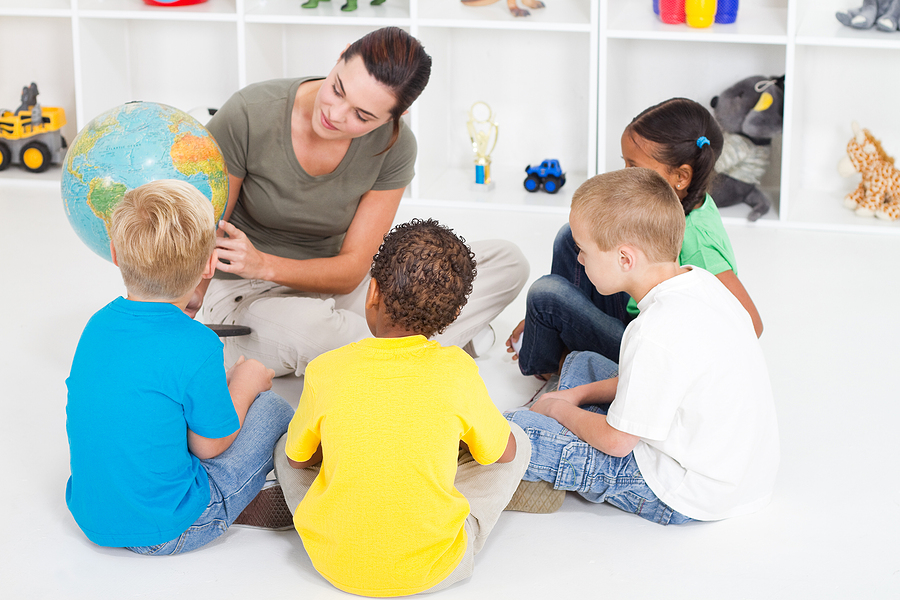 Preschool teacher showing students a globe.