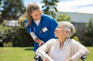 Female medical assistant caring for an elderly woman in a wheelchair. 