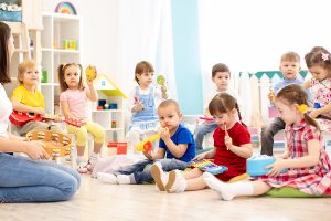 An early childhood educator sits in front of a group of young students. 