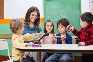 Female preschool teacher with a group of young students, teaching them a music lesson with instruments. 