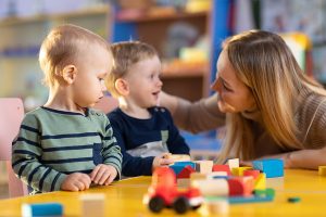 Young female teacher with two young students building with blocks. 