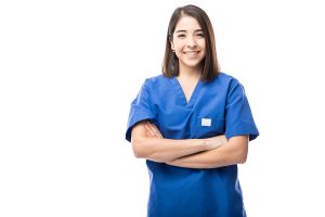 Female medical professional wearing blue scrubs and smiling at camera with her arms folded. 