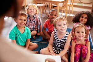Preschool teacher reading to a group of students during story time. 