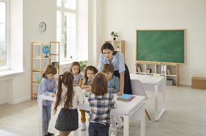 Female educator teaching a lesson to a group of students in her classroom. 