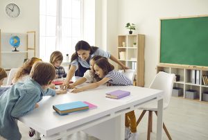 Female educator putting a puzzle together with her students in a classroom setting. 