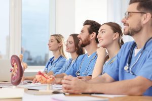 Group of vocational students wearing scrubs while listening to instructor teach a class. 