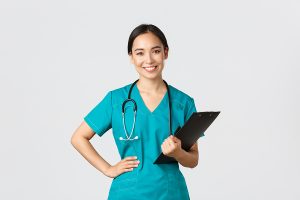 Female nurse wearing green scrubs and holding a clipboard. 