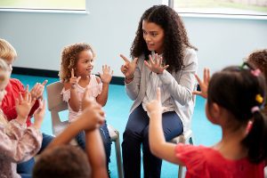 Female educator sitting in a circle with a group of students and learning how to count.
