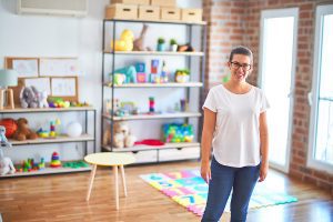 Female preschool teacher standing in her classroom smiling