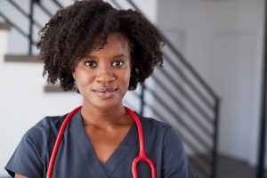 Female nurse wearing dark blue scrubs and a red stethoscope 