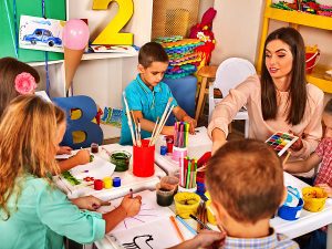 Female preschool teacher working on an art project with her students. 