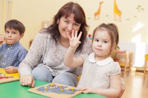 Female preschool teacher with students sitting at a table. 
