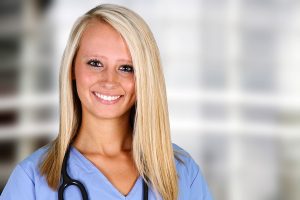 Closeup of a smiling female nurse in a hospital wearing blue scrubs.