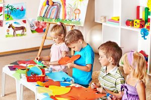 Young preschool aged children working on an art project at their table.