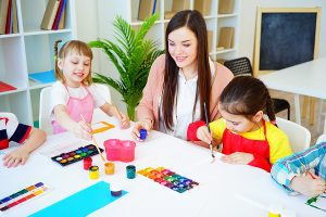 Preschool teacher painting with her students.