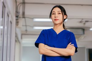 Confident female nurse wearing blue scrubs and standing in a medical facility. 